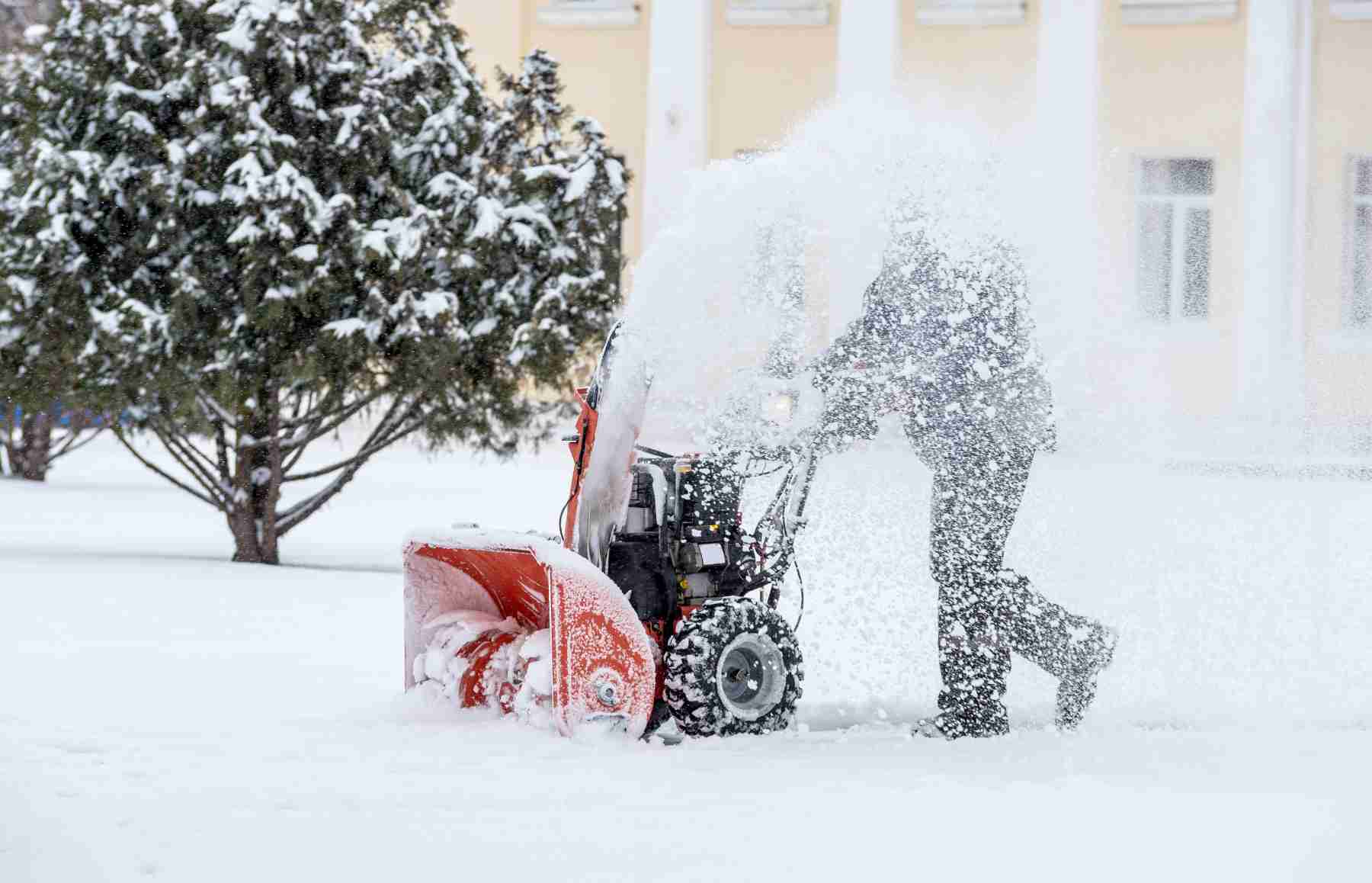 Professional snow removal service using a snowblower to clear a property during a heavy snowfall in Calgary