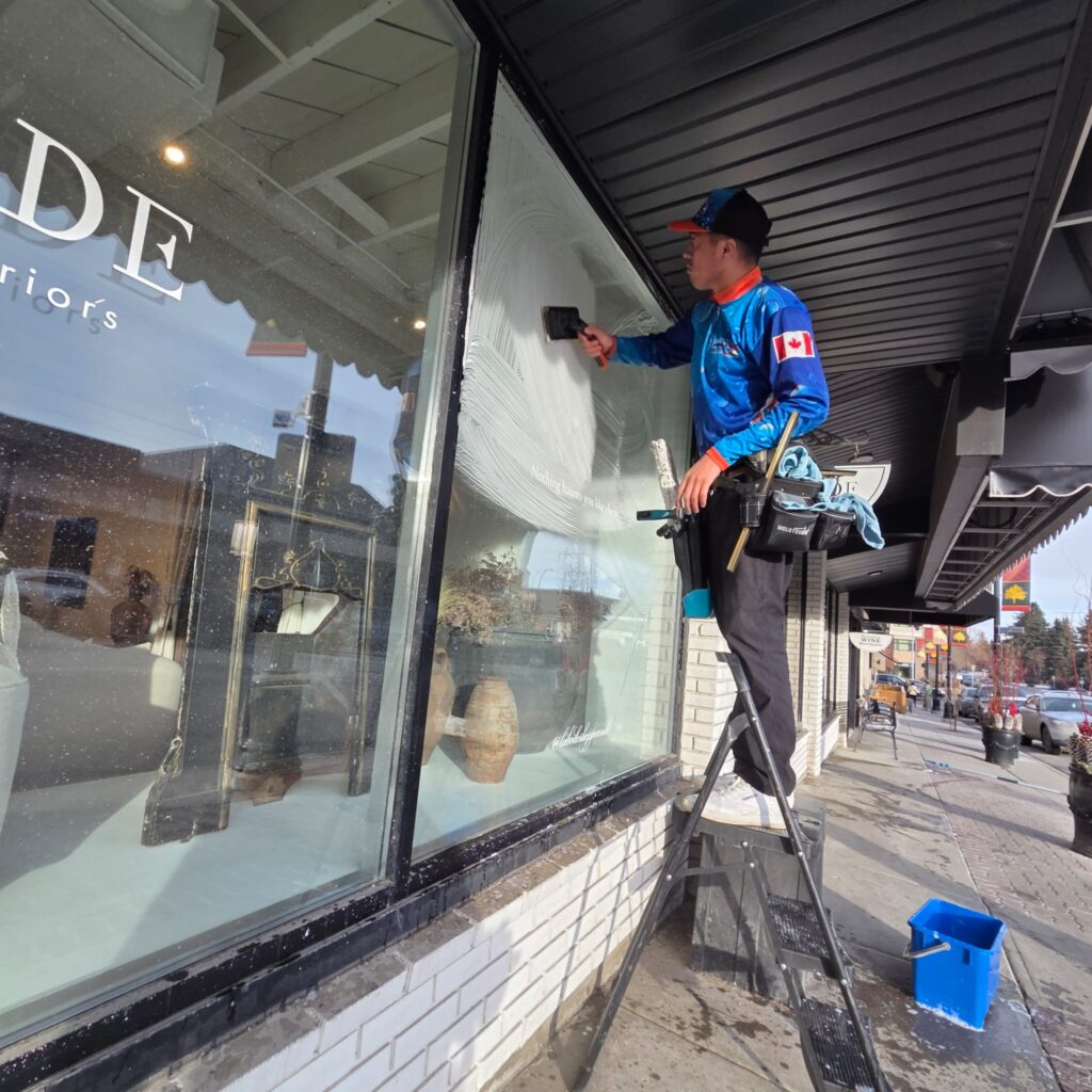 Window cleaner cleaning exterior business windows in Inglewood, Calgary.