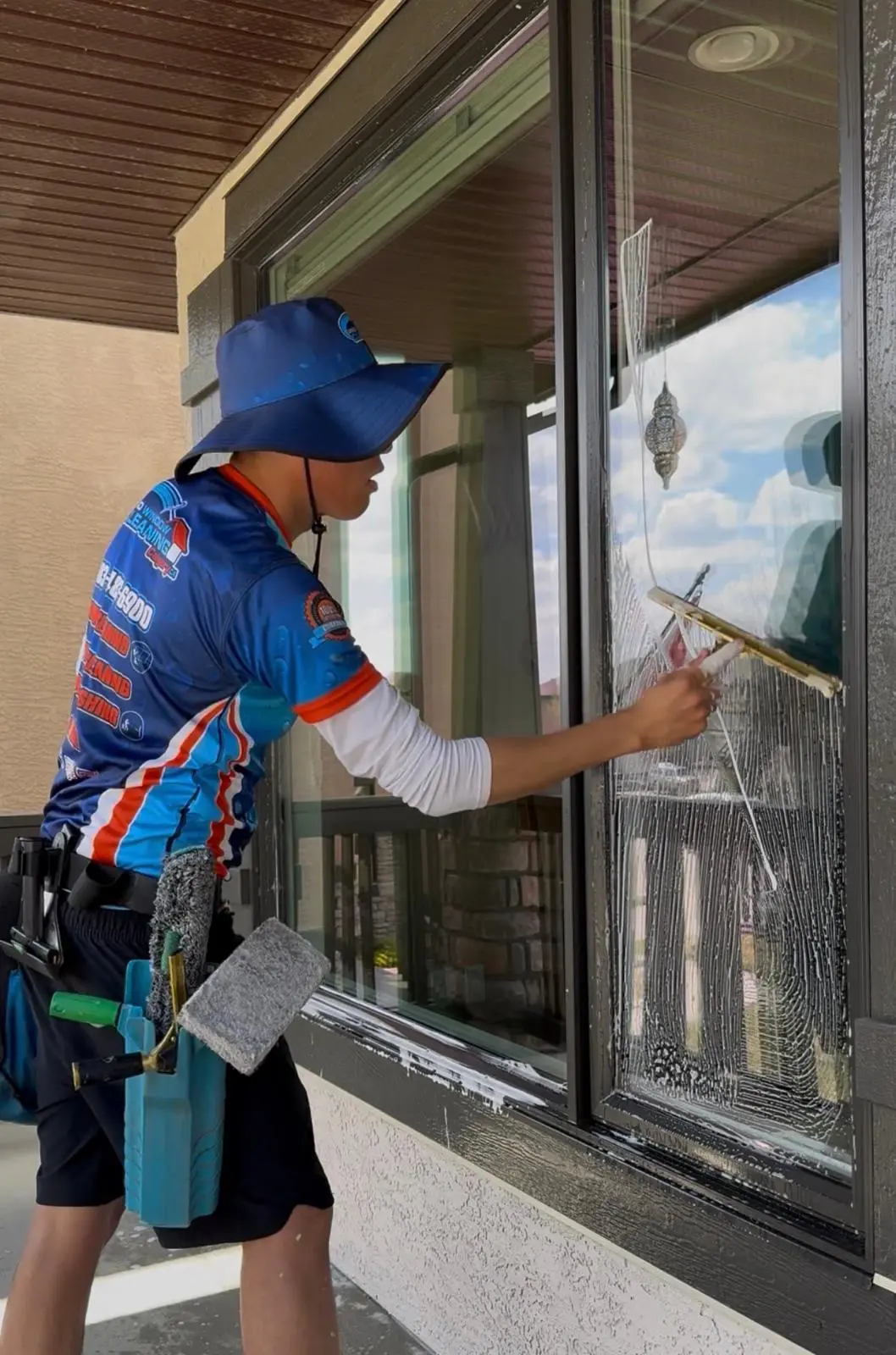 Pro Window Cleaning Calgary technician cleaning exterior windows with a squeegee on a Calgary home