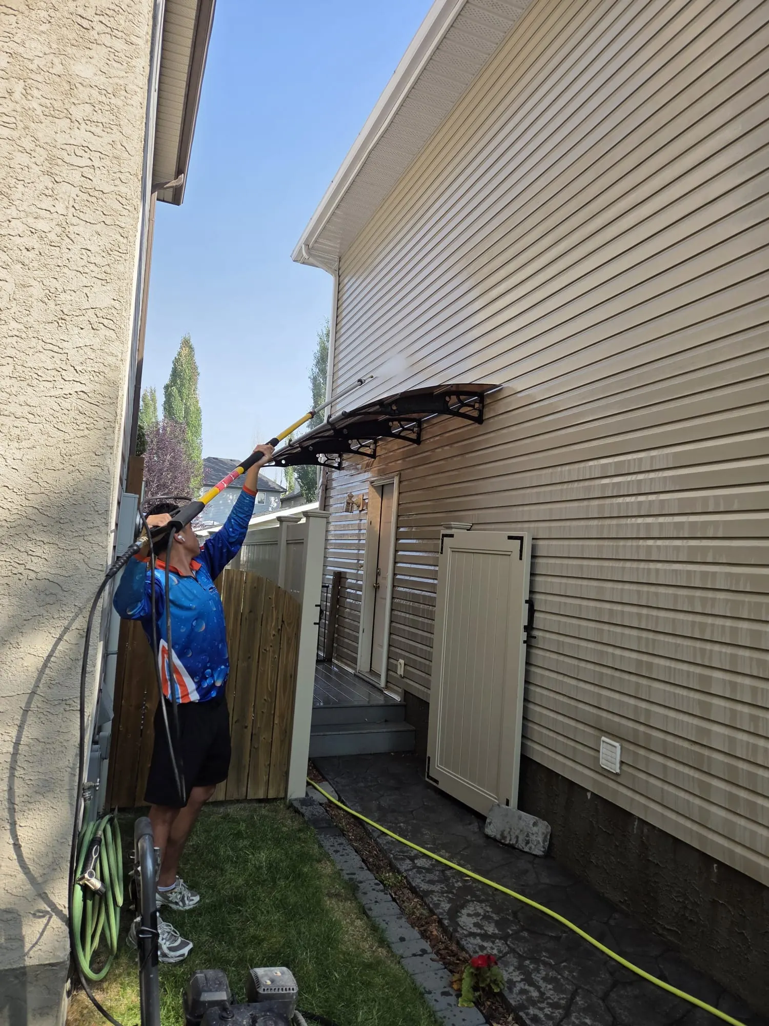 Pressure washing vinyl siding on a Calgary home