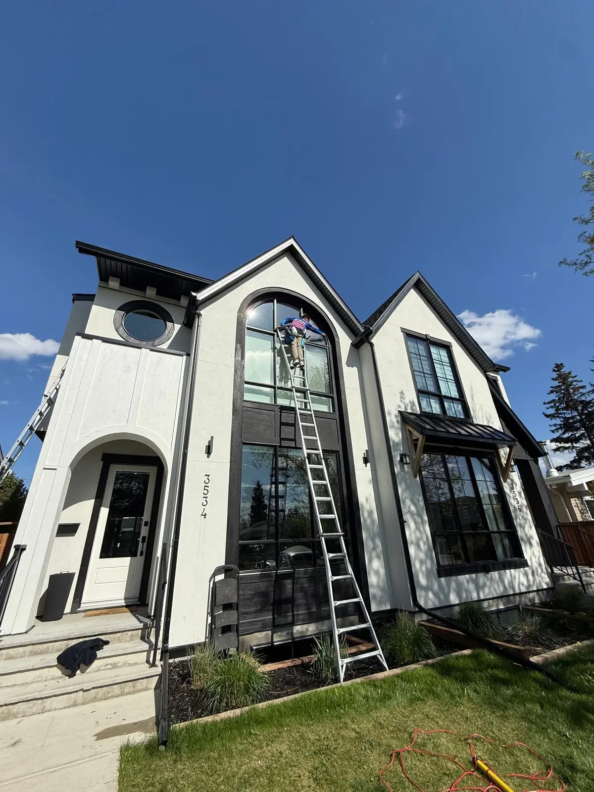 Pro Window Cleaning Calgary technician on a ladder cleaning high windows on a luxury Calgary home