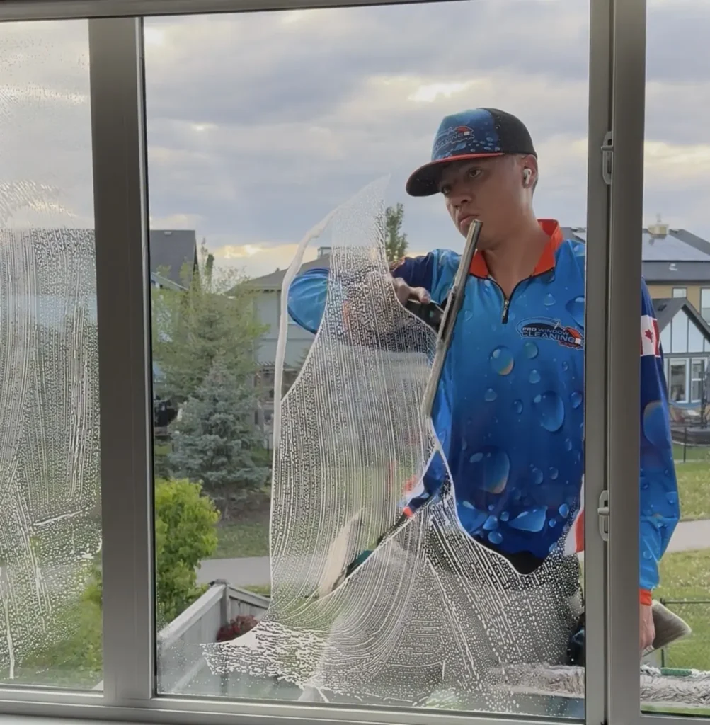 Window cleaner using a squeegee on the exterior windows of a Calgary home
