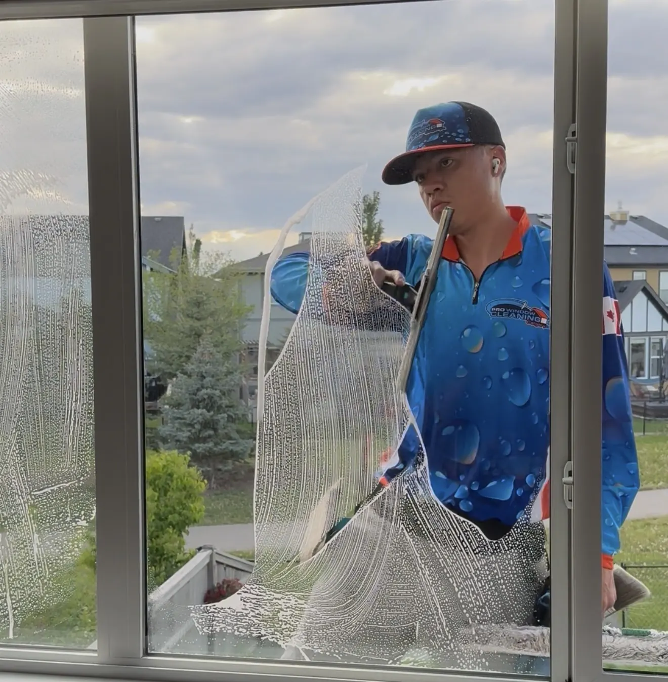 Window cleaner using a squeegee on the exterior windows of a Calgary home